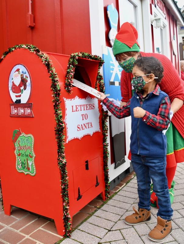 With some help from elf Nancy Bush, Ethan Foos is the first youngster to deposit a letter to Santa in the new mailbox in front of Citizens Bank on Second Street in downtown Lewes.