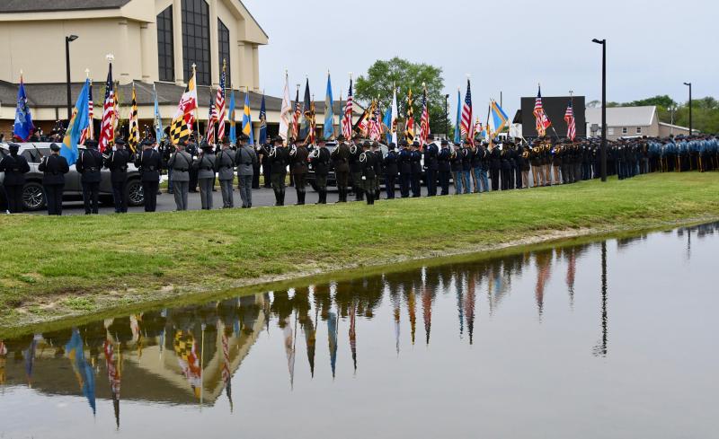 Police honor guards from troops throughout Delaware and Maryland stand at attention with raised flags in honor of Cpl. Keith Heacook.