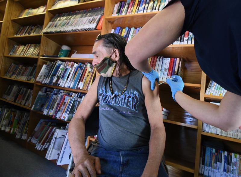 Luis Torres of Milton says he doesn’t like needles, so he looks away as he receives his first Pfizer vaccine from Beebe Healthcare RN Shanna Zickgraf.