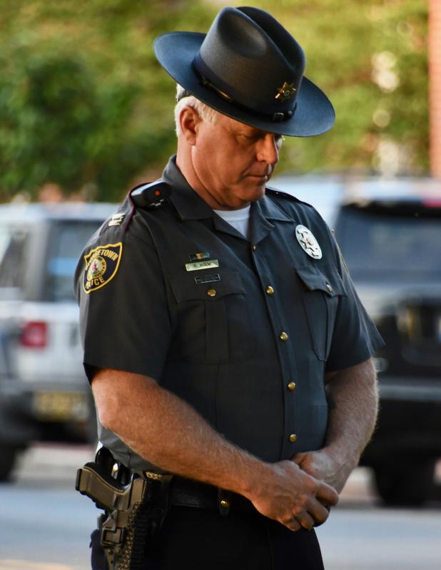 Georgetown Deputy Chief Ralph Holm bows his head as Georgetown Mayor Bill West offers an opening prayer.