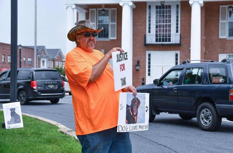 Jim Sekcienski holds a picture of his beloved canine and a sign saying Justice for Tank. DAN COOK PHOTOS