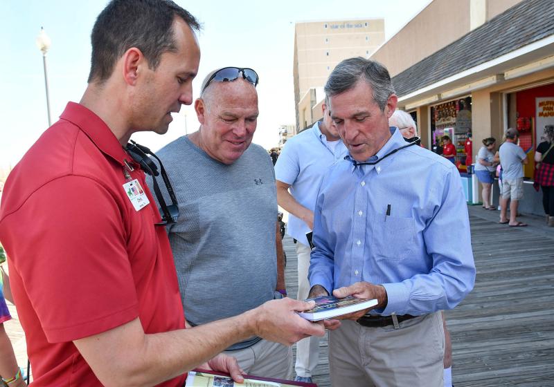 Funland owner Chris Darr, left, presents copies of “Land of Fun: The Story of an Old-Fashioned Amusement Park for the Ages,” to Rep. Pete Schwartzkopf and Gov. John Carney.