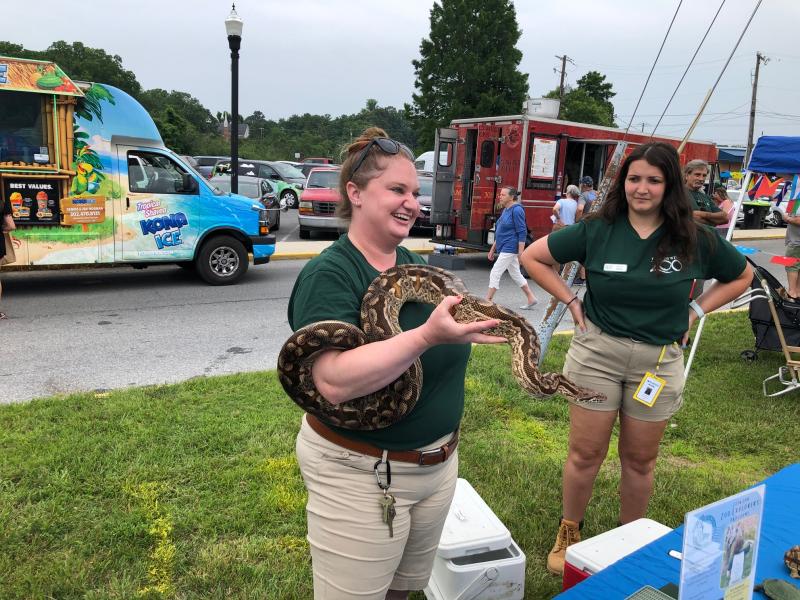 Daisy Fiore, left, and Leila Andrews of Brandywine Zoo do a demonstration with Bibi, a Dumeril’s boa and ambassador animal for the zoo. Bibi and her handlers take part in youth education events to help youngsters learn about snakes.