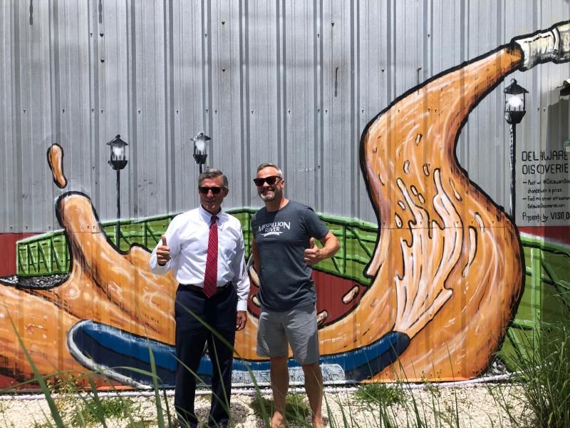 Gov. John Carney, left, and Mispillion River Brewing founder Eric Williams are shown in front of the Milford brewery. Mispillion was one of many businesses in Delaware to take part in the DE Wins business partnership, which provided incentives and deals to customers and employees who got vaccinated against COVID-19. RYAN MAVITY PHOTOS