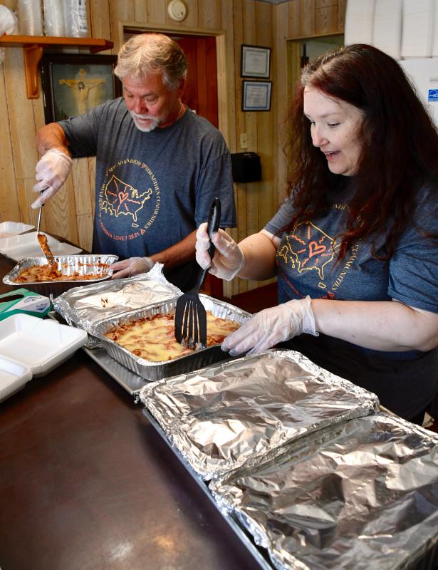 Carle Foster, of Lewes, and Jennifer Jarman, Delaware organizer for the Lasagna Love program, cut up trays of food to be placed in containers.