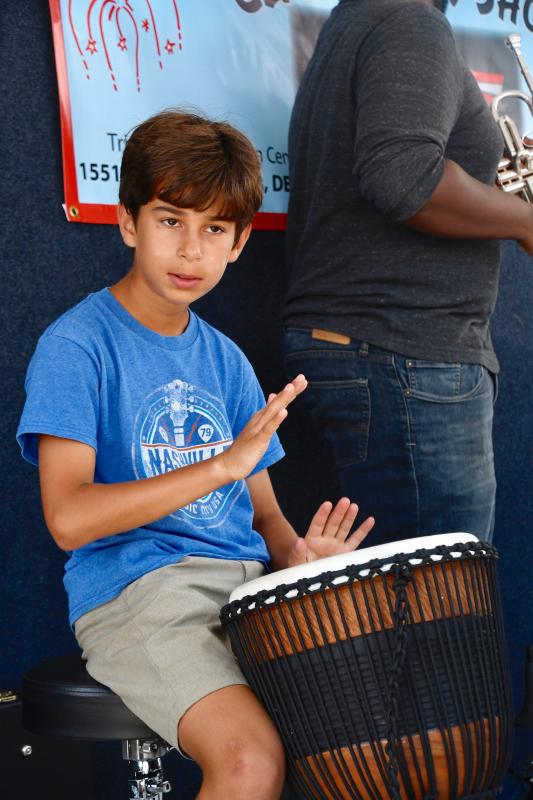 Bodhi Williams plays the bongos as part of the Williams Brothers Band performing at the Trinity Faith Christian Center July 4 celebration.