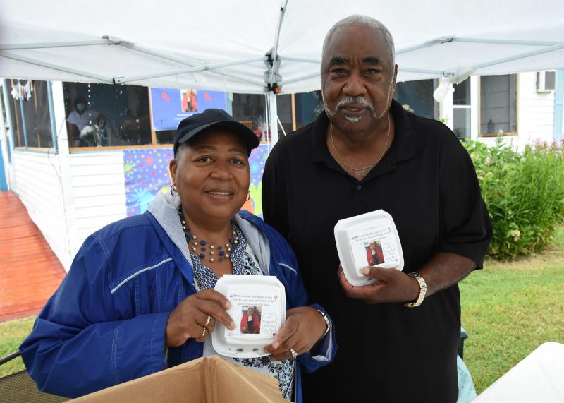 Daniels’ children Roslyn Harris, left, and Vance G. Daniels Sr. hold up the prepackaged cake they handed out to all those who stopped by to wish their mother a happy birthday. Harris is director of the Slaughter Neck Senior Center program, while Daniels is president of the Slaughter Neck Community Center.