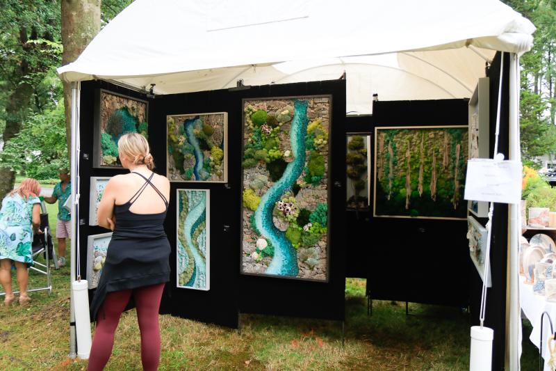 Visitors look at biophilic art work created by Stephanie Lavender. Lavender uses moss, cork and collected branches to create her pieces inspired by Mother Nature.