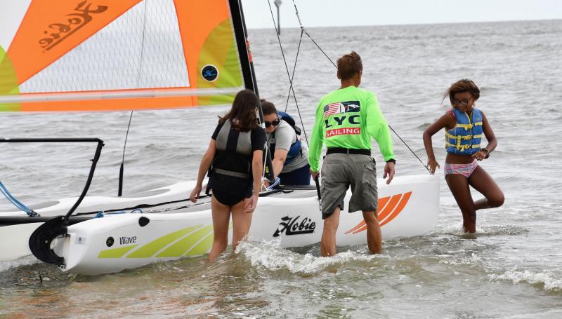 LYC Foundation President Chip Beaverson and LYC sailing instructor Anne Dolan help Iyana Johnson and Adryana Savage get off a sailboat.