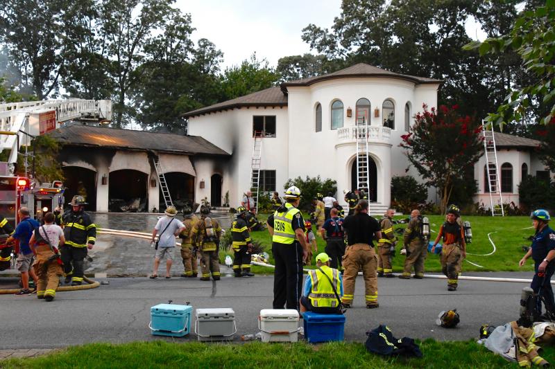 Volunteer firefighters from four companies responded to the blaze. After most of the fire was extinguished, firefighters gather on the lawn to cool off and drink water.