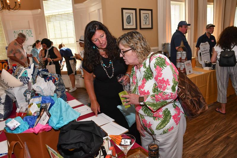 Christine Kirkley, left, and Debbie Berger bid on a shoulder bag at the silent auction.