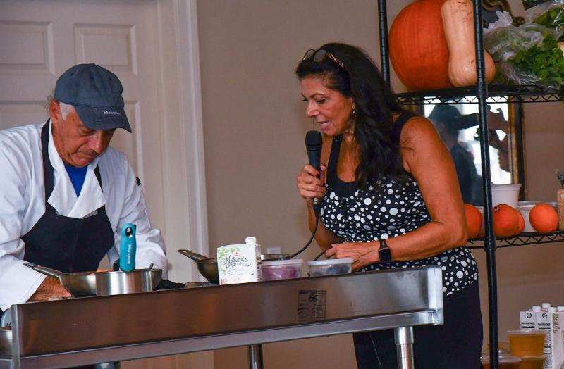 Founder and organizer of the Southern Delaware Wine, Food & Music Festival Stacy LaMotta, right, describes the food being prepared by Two Meatballs chef Franco Brattoli.