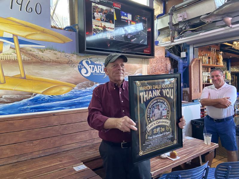 Commissioner Bill Stevens, right, beams as Mayor Dale Cooke shows party attendees the gift from the town.