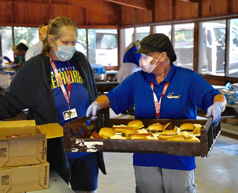 CHEER kitchen managers Beth Kirkey, left, and Theresa Podralski fill a tray with food.