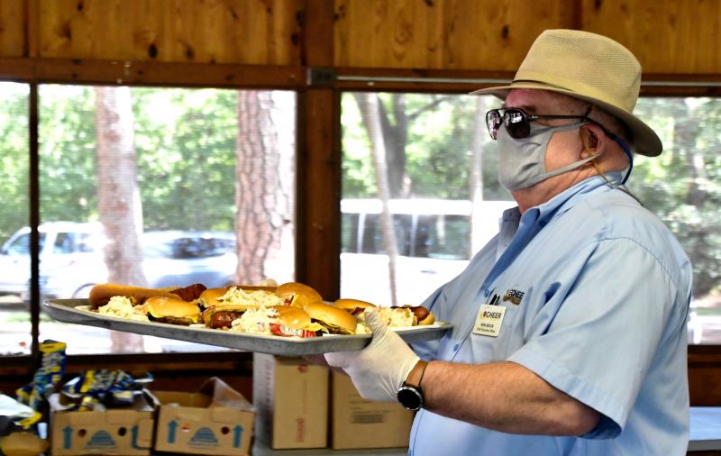 CHEER CEO Ken Bock helps his staff and volunteers by taking out a large tray of cookout essentials.