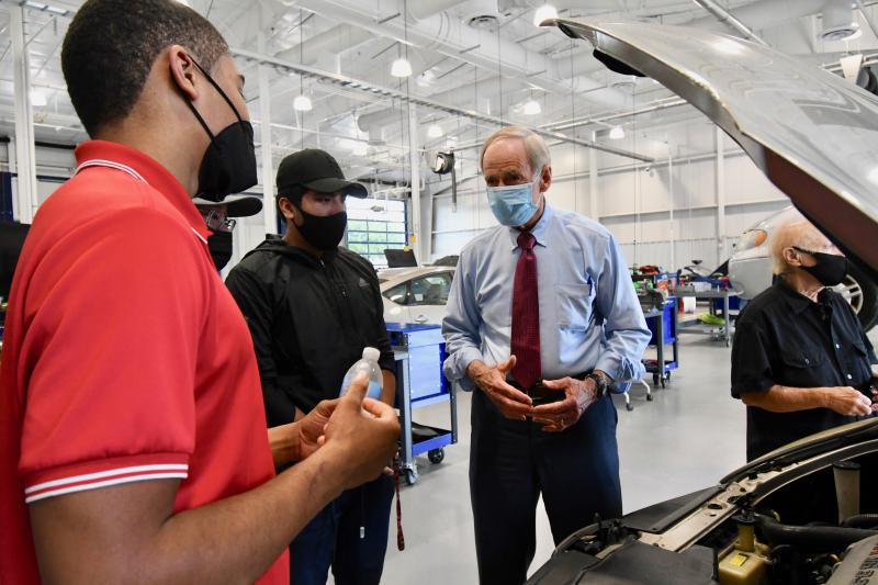 Students (l-r) Ronald Graham, Andrew Ochoa and Vinnie DiPoalo give U.S. Sen. Tom Carper a look under the hood during a tour of the facility.