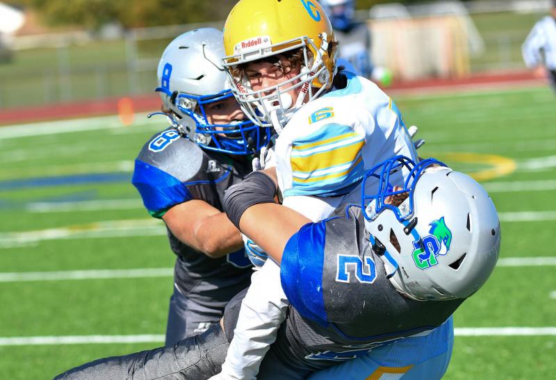 Cape’s Brenn Scott pounds for a gain before being pulled down by Jamie Righter-Hartman, left, and Kai Parkinson.