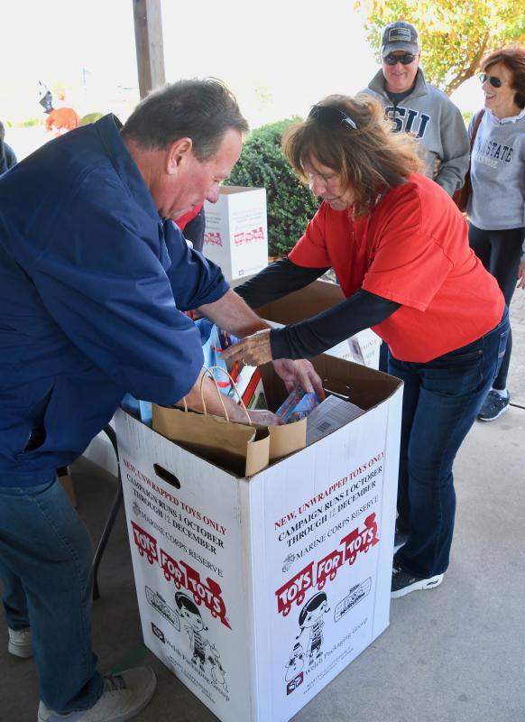 Volunteers Mike Flinn, left, and Nancy Anderson add donated toys to a box during the Toys for Tots kickoff celebration.