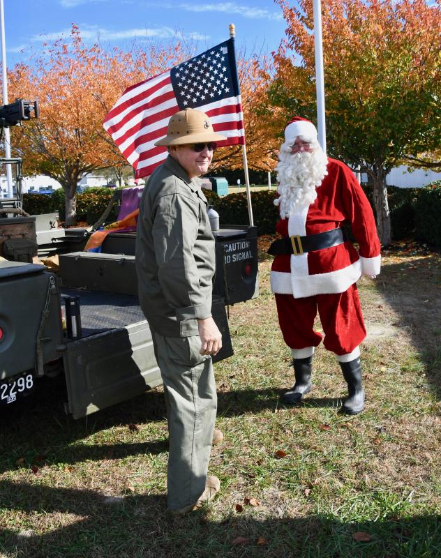 Santa Claus gets some firsthand information from World War II re-enactor Donald Hattier about a vintage Jeep.