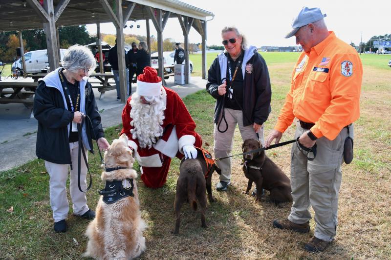 Santa Claus, aka Matt Lynch, gets up close and personal with dogs from Tri-State Canine Response Team and Delmarva Search and Rescue Group. In the photo are (l-r) Ruth Osman and Gail Hamman of Tri-State, and Paul Hamman of Search and Rescue.