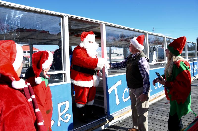 Lewes Mayor Ted Becker and a contingent of helper elves welcome Santa as he prepares to step off the water taxi.