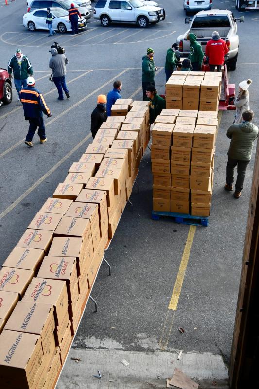Packed meal boxes sit on a long assembly line ready to be picked up by organizations for distribution.