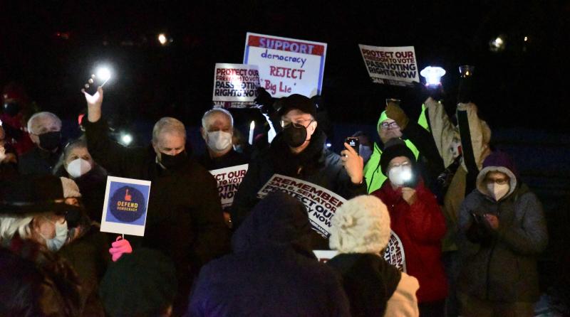 Some of the more than 200 people attending the vigil hold up their lights and signs.