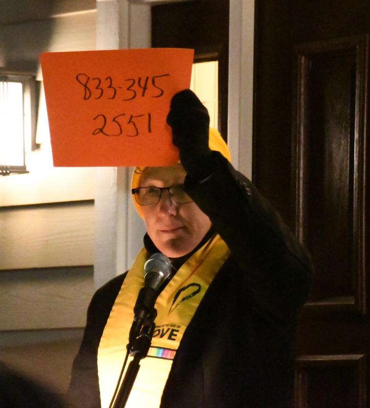 The Rev. Cathy Rion Starr displays a sign with the phone number of Sen. Chris Coons’ Washington, D.C. office. Those attending the vigil called the number and left messages urging Coons to push for voting reform and an end to filibustering.