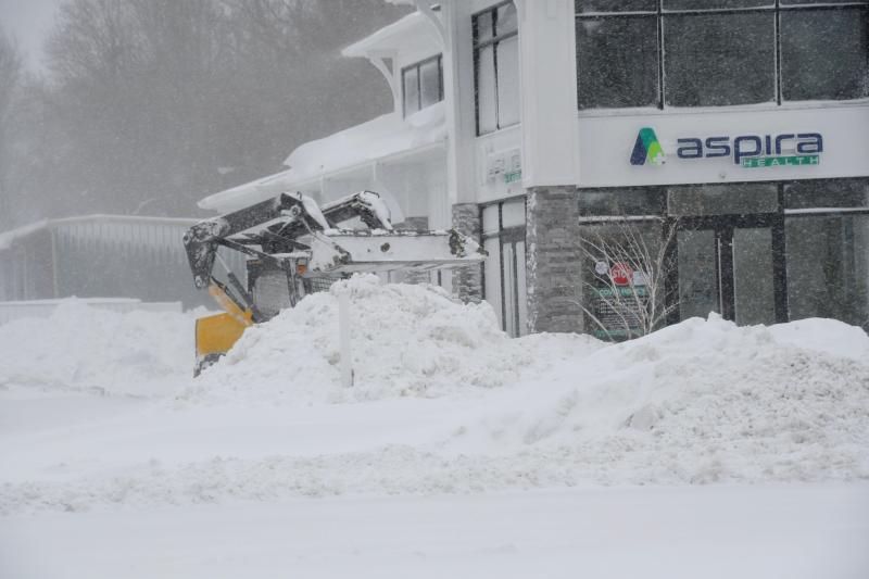 A small tractor adds to a large pile of snow from the parking lot of Aspira Health along Route 1 near Lewes. RON MACARTHUR PHOTO