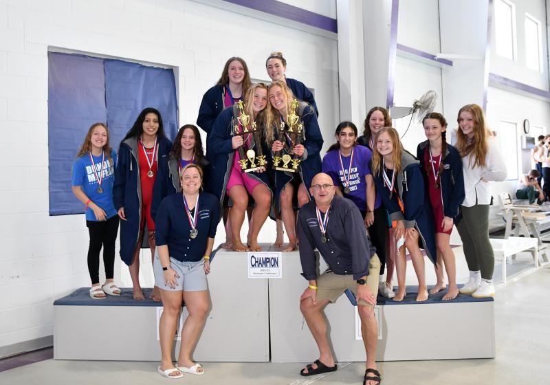 The Sussex Academy girls’ team poses with the dual-meet championship trophy and the Henlopen Conference tournament championship trophy. Shown in back are (l-r) Leni Kuska, Itzel Gomez Sanchez, Victoria Evans, Gracie Maughan, Sanne Elling, Elle McKay, Eve Mundok, Kimia Langroudi, Megan Raines, Addi McKay, Lyla Baker and Zoe Musil. In front are assistant coach Stephanie Hartsoe and head coach Tom Martiner.