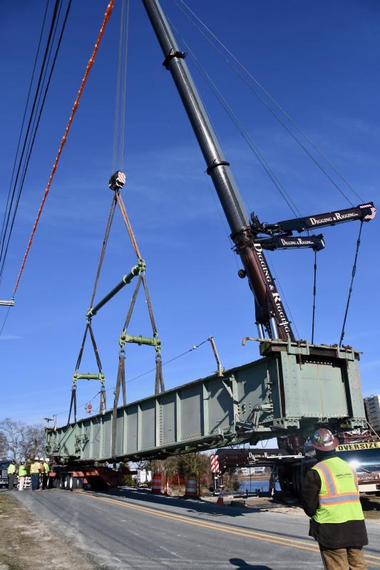 The swing bridge is lowered onto the rear section of the trailer as workers prepare to secure the 102-ton structure.