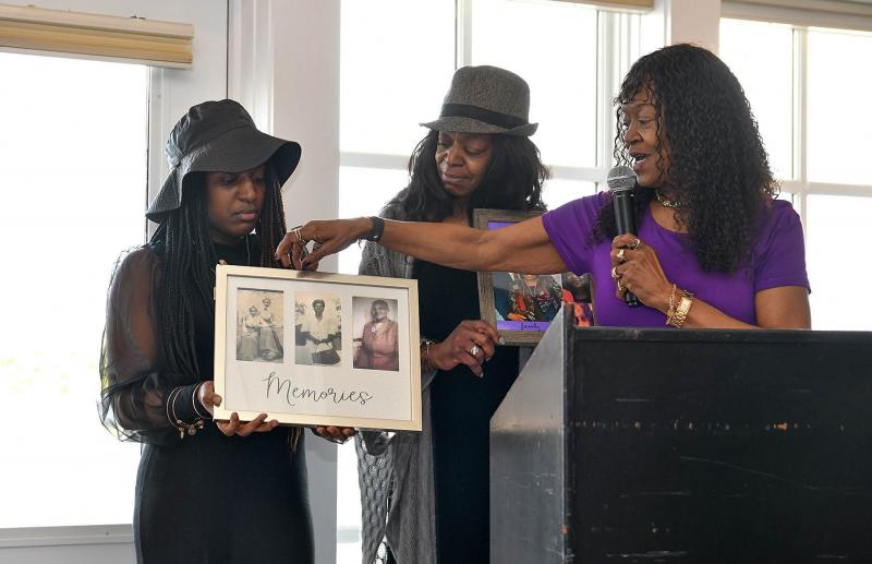 Presenting the Rev. George Edwards with photos of his family are (l-r) granddaughter Joleesha Edwards, and daughters Lisa Edwards and Georgia Perry.