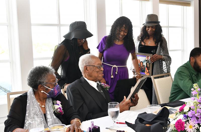 Presenting the Rev. George Edwards with photos of his family are (l-r) granddaughter Joleesha Edwards, and daughters Georgia Perry and Lisa Edwards.