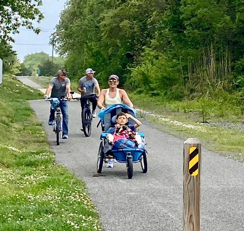 Sara Carter wheels Mason along the Lewes-to-Georgetown Trail as husband Matt and father Dan Stephens ride along with her.