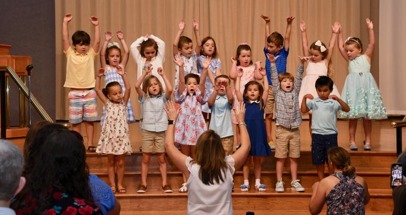Members of the Pelican Class sing on stage. In back are (l-r) Carter Coveleski, Rose Skonieczki, Emmery Wiest, Grayson Rhine, Cora Bloom, Kaylee Castelli, Webb Ciavarra, and Josephine and Juliette Miller. In front are Charlotte Forrest, Blake Brewer, Caroline Harvey, Grant Carr, Piper Graviet, Brody Feindt and Nico Sorto.