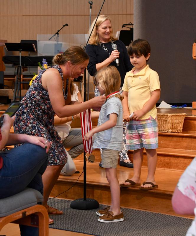 Pelican Class teacher Carrie Dare awards graduation medals to students Blake Brewer and Carter Coveleski as Epworth Preschool Director Betsy Plowman looks on.