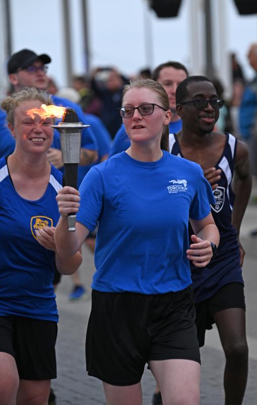 Rehoboth Beach seasonal police Officer Marie Fuller keeps an eye on the torch as she takes the first few steps toward Grove Park.