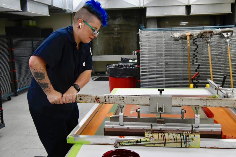 Samantha Leister pulls ink across a screen as part of the sign-screening process in the busy DelDOT sign shop in Dover. The shop is responsible for about 99% of the signs along the state’s roadways. RON