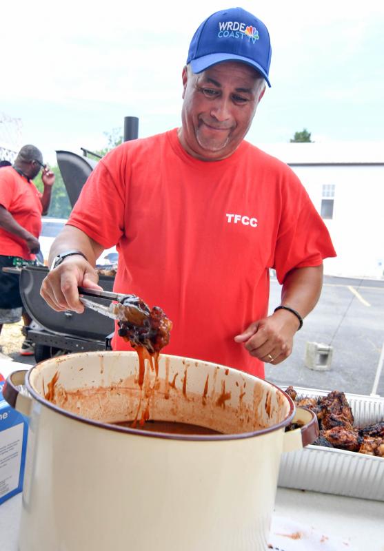Volunteer Clarence Harmon gets the chicken sauced up at the food booth while Lloyd Griffin keeps the poultry cooking.