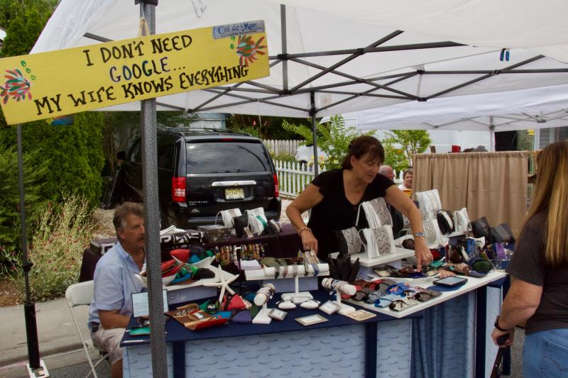 Louis Strauss, who fabricates fish skin into leather products such as wallets, abides by the sign as Lisa Strauss explains their offerings to a potential customer.