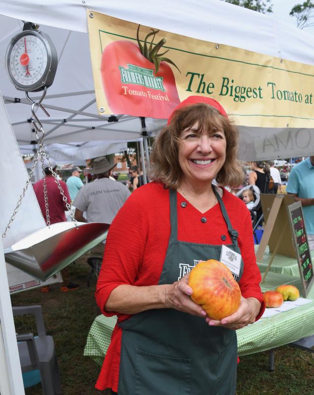 Market volunteer Rosalind Johnson displays one of the tomatoes vying for the largest one of the day.