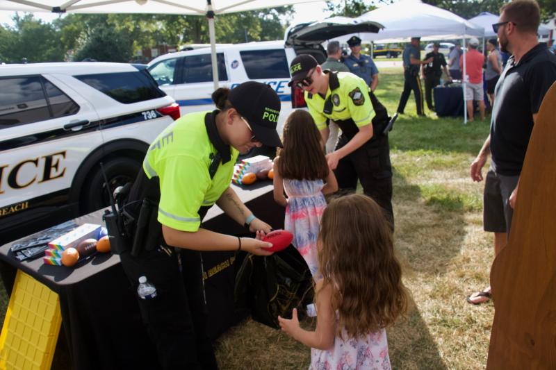 Rehoboth Beach police officers Story and Maciejewski hand out goodie bags to Leah, 7, and Alyssa, 4, both of Port Chester, N.Y. Their father Ken Manning looks on.