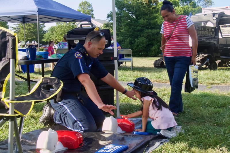 Sussex County Paramedic Jordan Dattoli shows Carla, 5 from Lincoln, how to properly administer CPR. Her mother Antonia Garcia looks on.