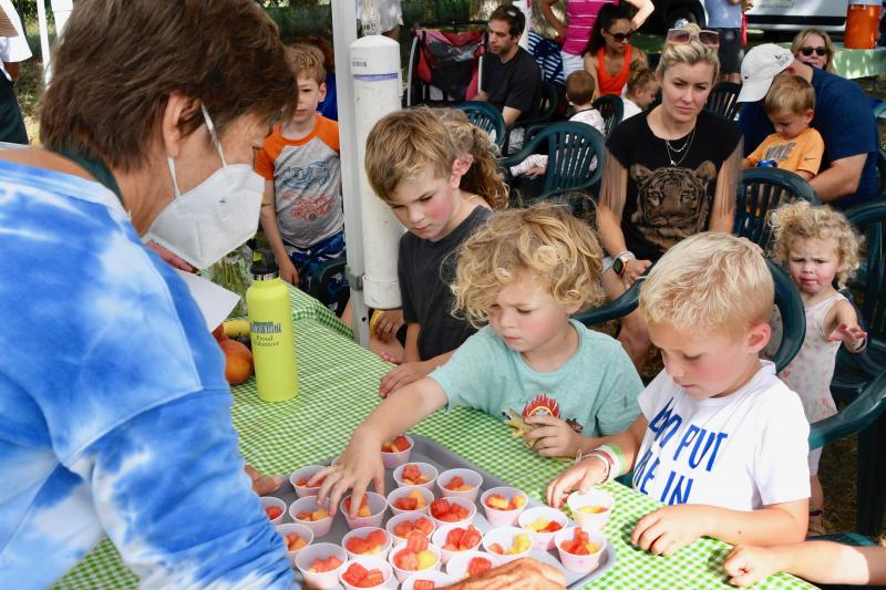 Children line up to get fruit treats from Lewes market volunteers as their parents learn how to pack nutritious school lunches.