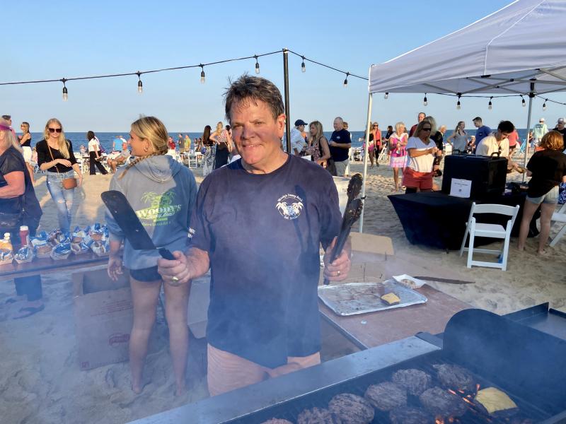Woody’s Dewey Beach owner and Dewey Business Partnership Vice President Jimmy O’Conor flips burgers at the grill all evening. ELLEN DRISCOLL PHOTO
