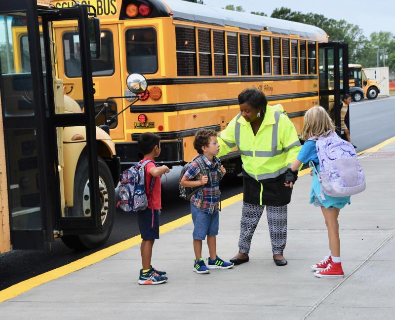 Lewes Elementary School paraeducator Kim Hall helps students as they unload from their bus. RON MACARTHUR PHOTO