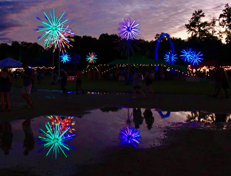 Lights are reflected in leftover puddles from a brief rainstorm just before concerts got underway on the first day of Firefly. RON MACARTHUR PHOTO