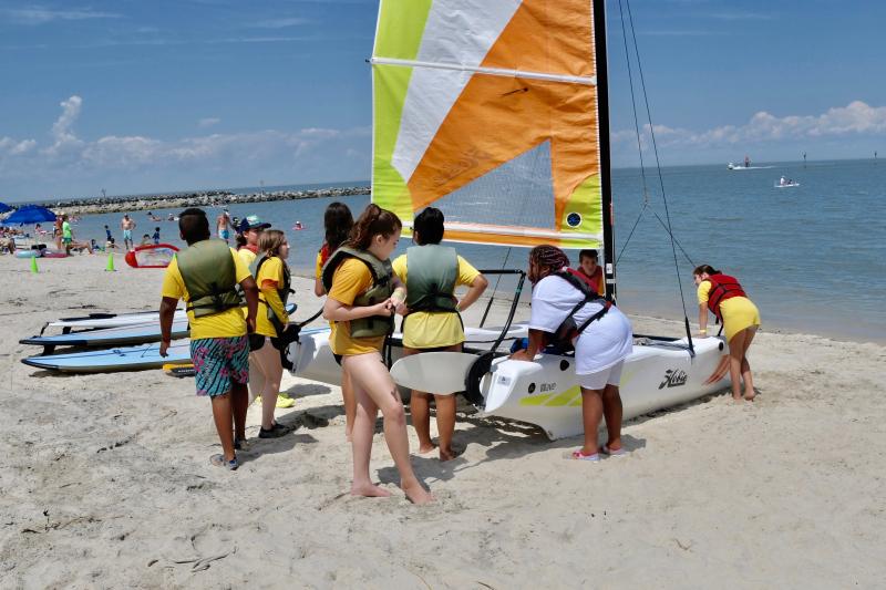 With the help of Lewes Yacht Club Foundation members and sailing school staff, YMCA campers get a Hobie ready to launch off Lewes Beach.