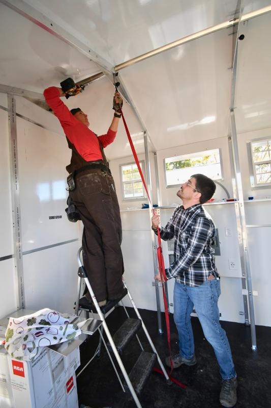 Volunteers Jackie Erley, on ladder, and Michael Digiacoma are nearing completion of construction of one of the Pallet shelter units.