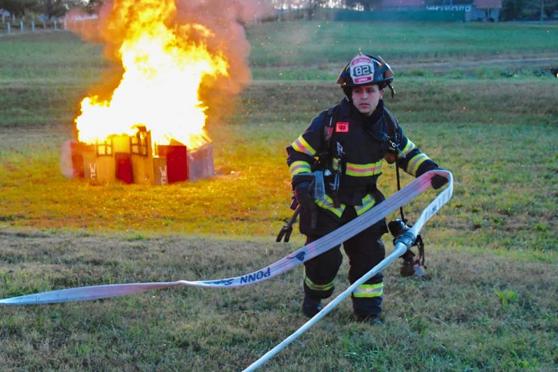 Lewes firefighter Joe Esposito gets a hose in position so other volunteers can put out the fire blazing behind him.